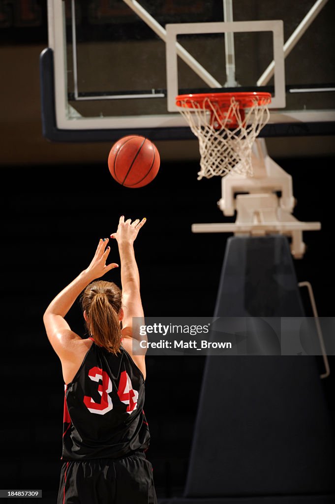 Female basketball player throwing a free throw toward basket