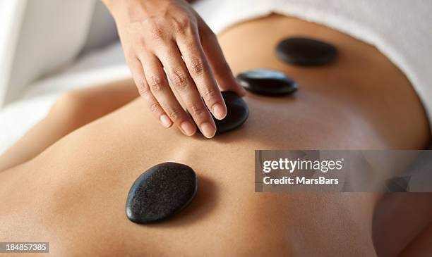 hot stone massage therapy - rug handen zij stockfoto's en -beelden