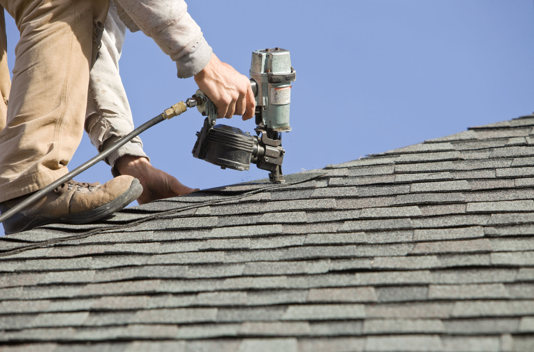 Roofer Nailing Cap Shingle to a New House Roof Roofer Nailing Cap Shingle to a New House Roof
