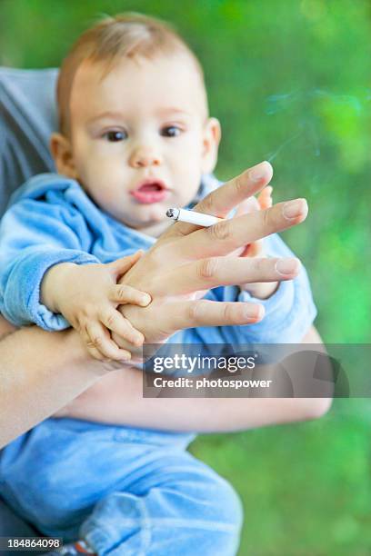 a little baby behind a hand with a lighted cigarette - extreme close up baby stock pictures, royalty-free photos & images