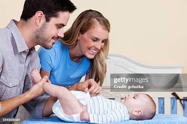 parents changing baby diaper - gchutka stock pictures, royalty-free photos & images