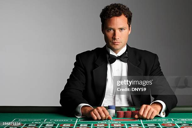 el rodillo sentado en la mesa de ruleta con sus apuestas chips - esmoquin fotografías e imágenes de stock