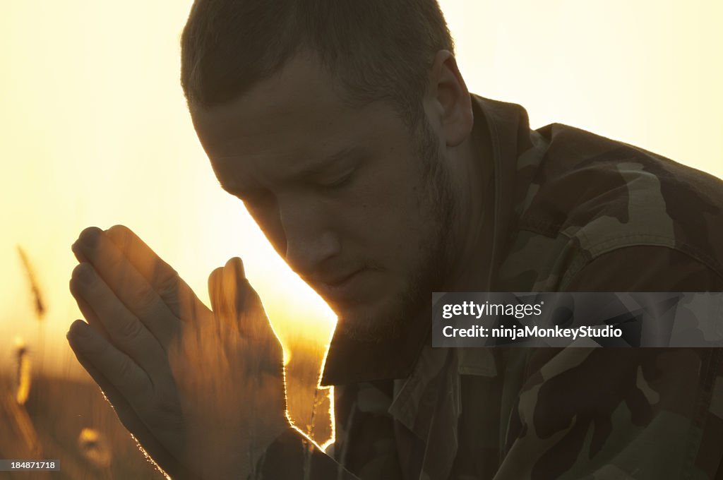 Militärische Mann Beten, allein in den goldenen Sonnenuntergang