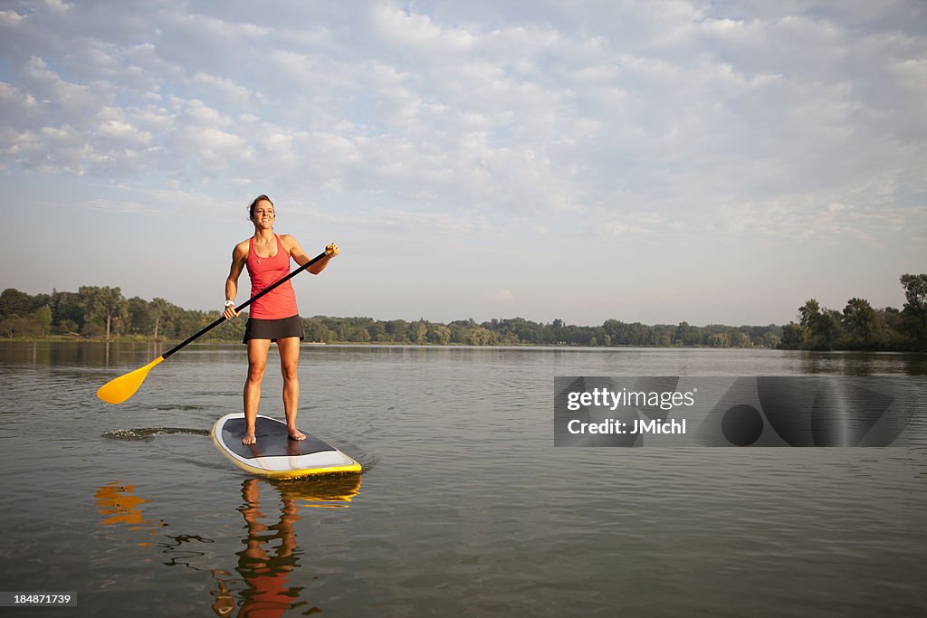 Femme avec pagaie se dresse le paddleboard à l'eau