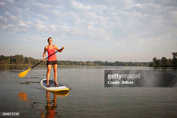 woman with paddle stands on paddleboard in water - paddle boarding bildbanksfoton och bilder