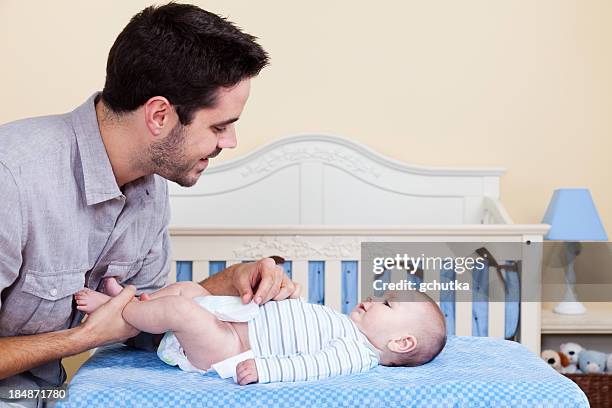 father changing baby diaper - gchutka stock pictures, royalty-free photos & images