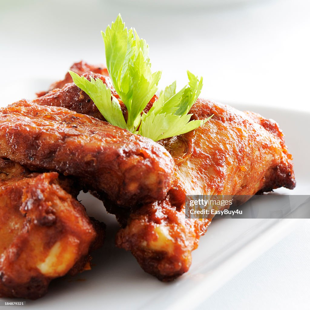 A white plate full of spicy chicken wings