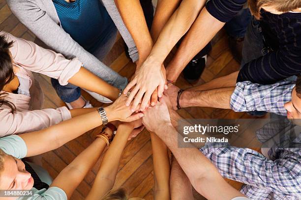 circle of people with their hands in the center - handen ineengevouwen stockfoto's en -beelden