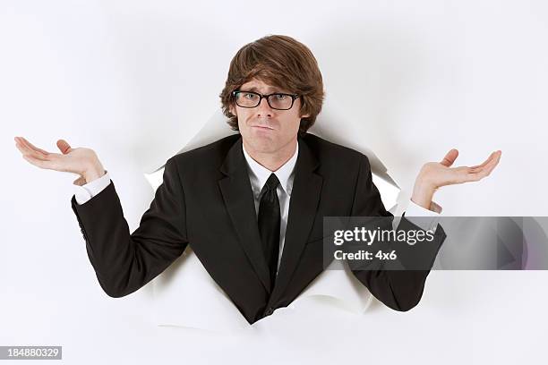 businessman emerging through hole in paper and making face - shrugging stock pictures, royalty-free photos & images