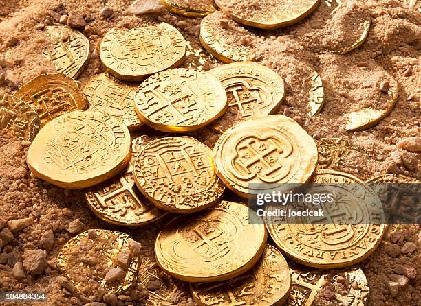 gold doubloons - buried in sand stockfoto's en -beelden