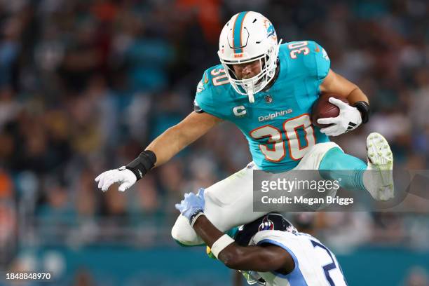 Alec Ingold of the Miami Dolphins hurdles over Roger McCreary of the Tennessee Titans in the fourth quarter at Hard Rock Stadium on December 11, 2023...
