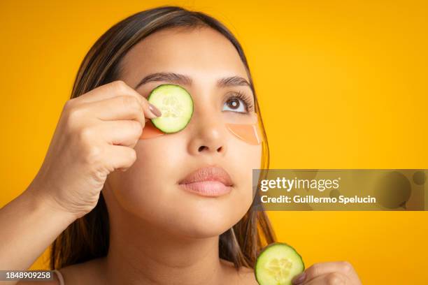 young woman applying cucumber and eye mask during her skin care - cucumber eye mask stock pictures, royalty-free photos & images