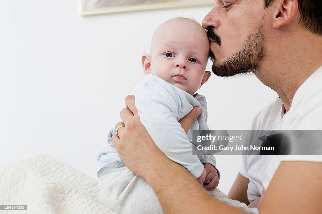 Dad kissing baby tenderly