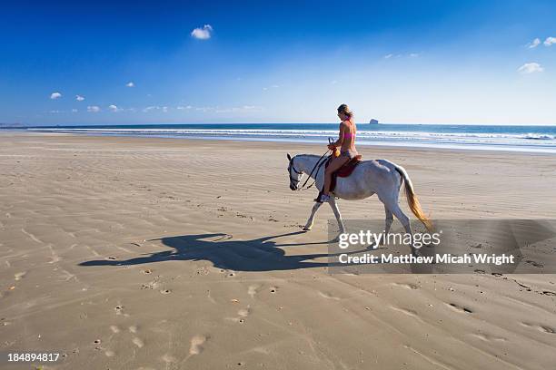 a woman rides a hose along the beach. - san juan del sur stock pictures, royalty-free photos & images