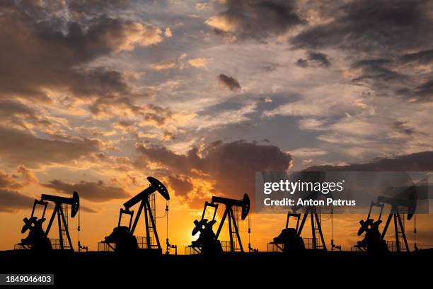 oil field with rigs at sunset. world oil industry - industrie du pétrole photos et images de collection