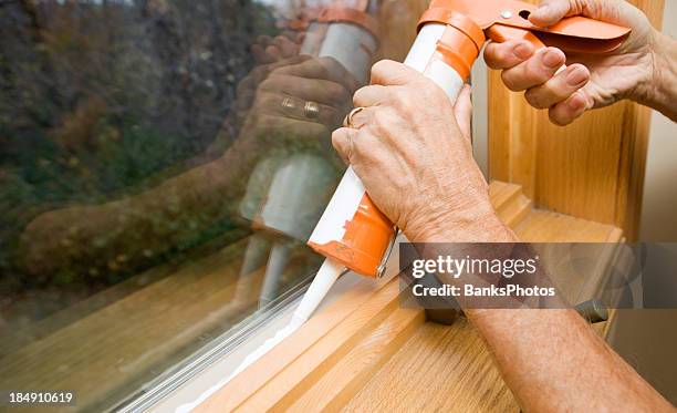 hands applying weather seal caulk to window frame - caulk stockfoto's en -beelden