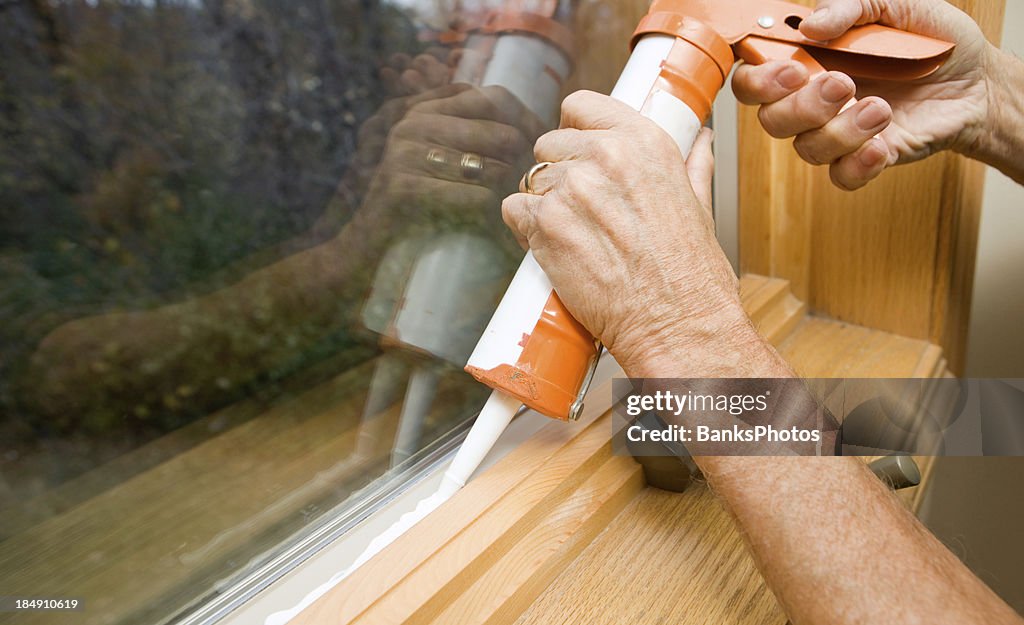 Hands Applying Weather Seal Caulk to Window Frame