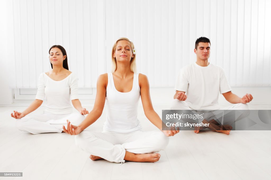 People working yoga. They are sitting in lotus pose.