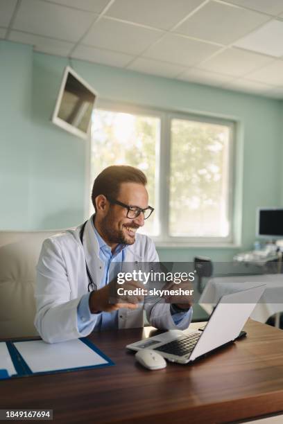 happy male doctor working on laptop in the office. - doctor using laptop stock pictures, royalty-free photos & images