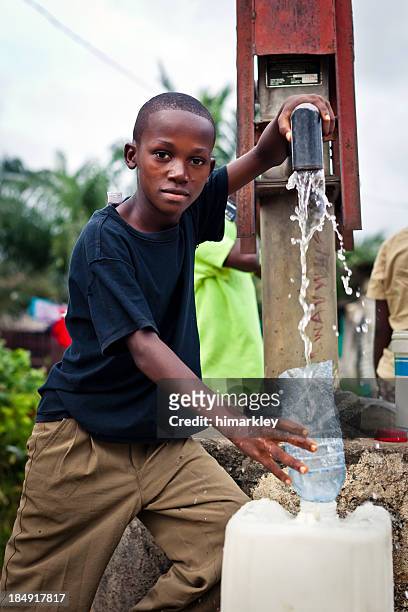 african boy by water pump - african africa child drinking water cup stock pictures, royalty-free photos & images