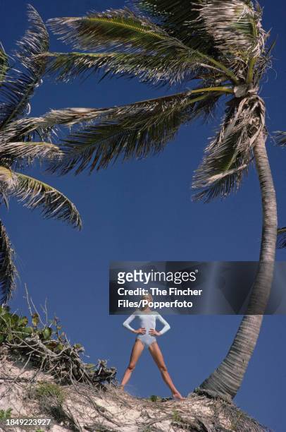 British model Jilly Johnson posing between two palm trees at Crane beach in Barbados, circa 1976.