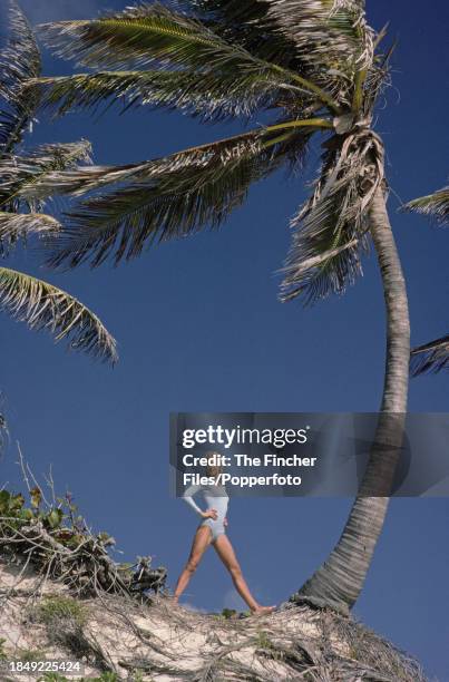 British model Jilly Johnson posing between two palm trees at Crane beach in Barbados, circa 1976.