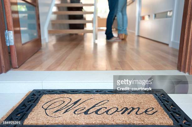 happy young couple standing inside their new house - doormat stock pictures, royalty-free photos & images