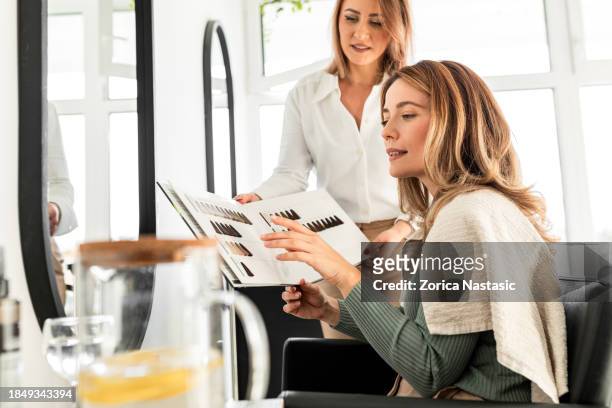 young adult woman and hairdresser discussing hair dye shades - blonde hair dye stock pictures, royalty-free photos & images