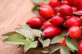 Close up of rose hip berries and leaves on wooden table