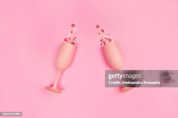 pastel millennial pink valentine's day background with two champagne glasses on pink background with red and white heart shaped confetti.  flat lay, top view, copy space. trendy retro 80's, 90's  romantic backdrop - top lay wine stock-fotos und bilder