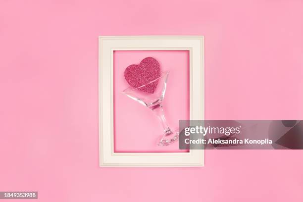 creative layout made with cocktail glass, pink shiny heart and white picture frame on pastel pink background. flat lay, top view, copy space for text. trendy retro 80's, 90's  romantic backdrop. - 2000s style photos et images de collection