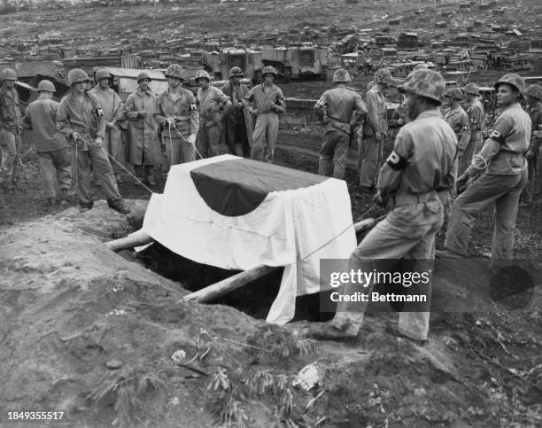 American military policemen lower the flag covered casket, containing the remains of Japanese Lieutenant General Yoshige Saito of the Imperial...