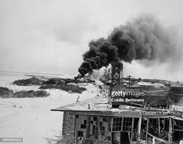 Smoke from a American bombed and burning buildings on Midway Island during the battle of Midway between the U.S. Navy and the Imperial Japanese Navy,...
