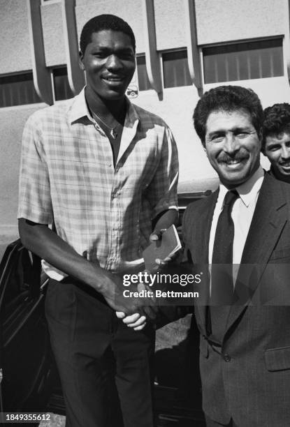 Nigerian-American NBA basketball player Hakeem Olajuwon, currently with the Houston Rockets, gives an handshake to his attorney, Robert Rivkind,...