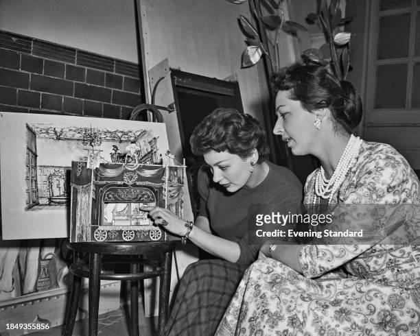 British soprano Adele Leigh pointing at a detail of a model theatre stage, May 1st 1957. At right is a woman named as Margaret Ellis.