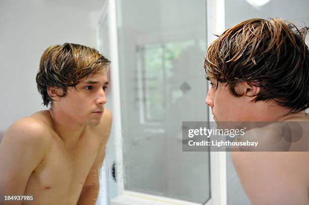 männlicher teenager, die sein gesicht im spiegel im badezimmer - boy taking a shower stock-fotos und bilder