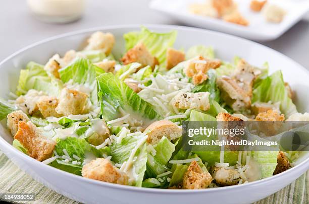 a bowl of caesar salad with croutons and cheese on table - crouton stockfoto's en -beelden