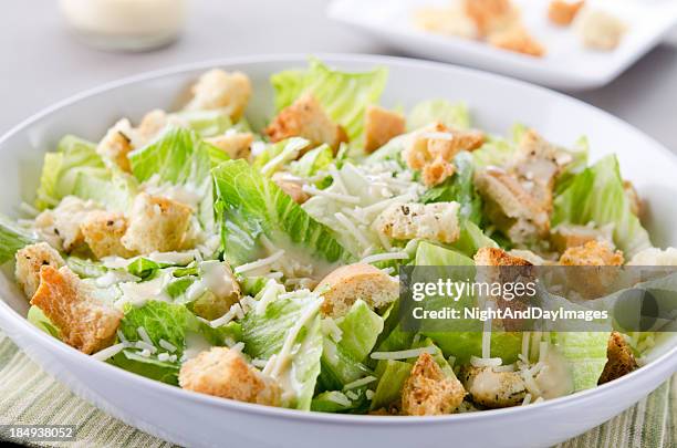 a bowl of caesar salad with croutons and cheese on table - romaine lettuce stock pictures, royalty-free photos & images