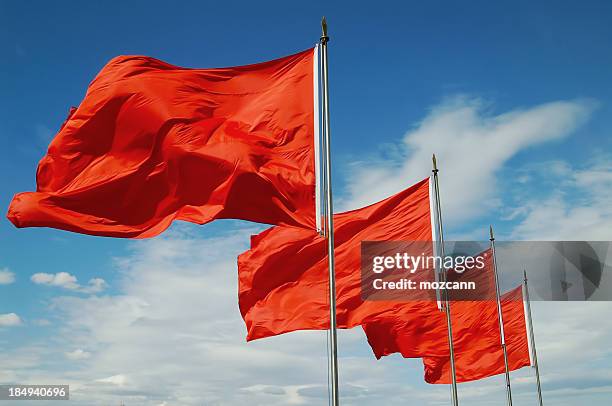 a row of red flags blowing in the wind - red flag stock pictures, royalty-free photos & images