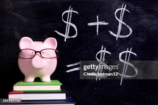Piggy bank on top of books with money signs on black board Piggy bank on top of books with money signs on black board
