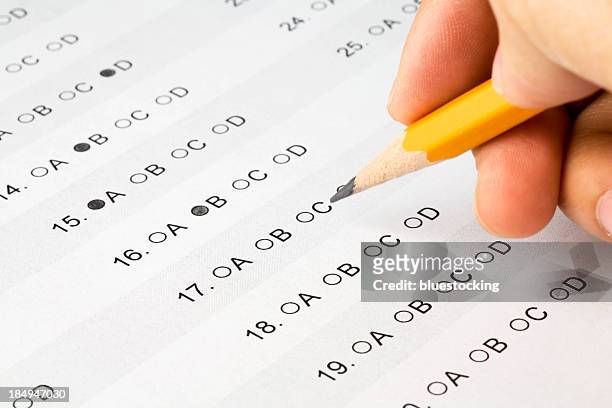 pencil held over a multiple choice exam - exam preparation stock pictures, royalty-free photos & images