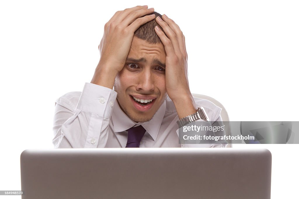 Man staring at laptop with shocked and desperate expression