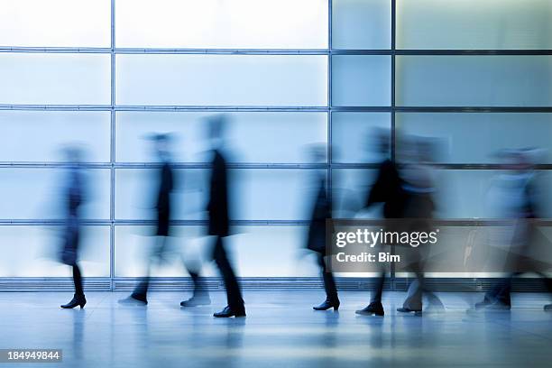 commuters walking in modern glass interior, blurred motion - shopping abstract stockfoto's en -beelden