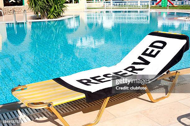 lounge chair next to pool with 'reserved' towel - reclining chair stock pictures, royalty-free photos & images