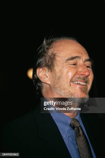 American film director and screenwriter Wes Craven, wearing a black jacket over a blue shirt, attends the Westwood premiere of 'Scream', held at Avco...