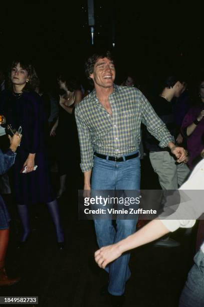 American actor Bryan Cranston, wearing a checked shirt and jeans, dancing at a cast party for the soap opera 'Loving', United States, circa 1984.
