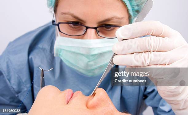 doctor performing plastic surgery - human nose stockfoto's en -beelden