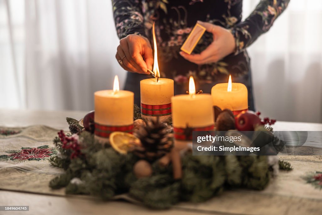 A woman lights the last fourth candle on an Advent wreath during Christmas Eve.