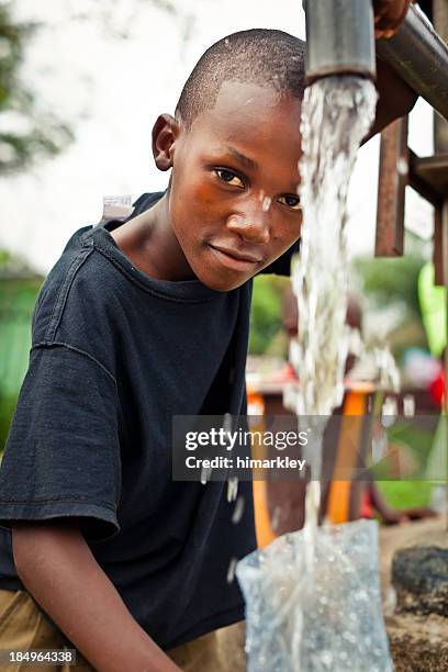 african boy by water pump - african africa child drinking water cup stock pictures, royalty-free photos & images