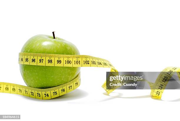 a measuring tape around a granny smith apple isolated - tape measure stock pictures, royalty-free photos & images